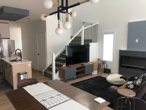 sala de estar con sofá, mesa y escalera en Southpointe_Homestay, en Fort Saskatchewan