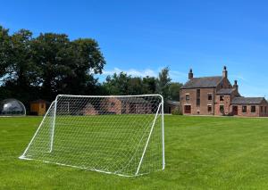 a soccer goal in a field with a house in the background at Manor House Farm 