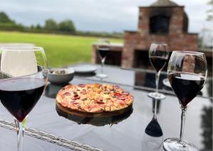 a table with two glasses of wine and a pizza at Manor House Farm 