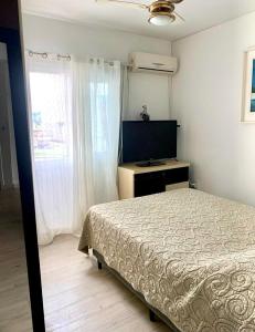 Un dormitorio con una cama y un televisor de pantalla plana. en Apto 3 dorm completo - 100m Praia - Meia Praia, en Itapema