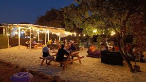 a group of people sitting on benches in a park at night at Skippers - Adults only in Ukunda