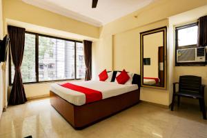 a bedroom with a bed and a mirror and a chair at Hotel Lal Sai Residency in Mumbai