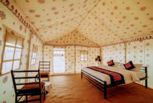 a bedroom with a bed and two chairs in it at Husain desert Safari Camp in Jaisalmer