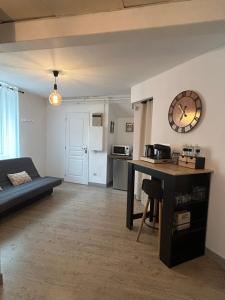 a living room with a table and a clock on the wall at Suite parentale 50m2 in Châtillon-Saint-Jean