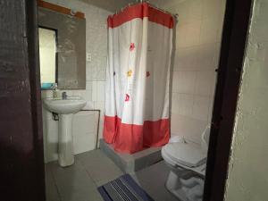 baño con cortina de ducha roja y blanca y aseo en Hostal Fernanda, en Santa Cruz