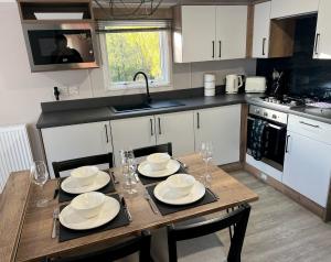 a kitchen with a wooden table with plates and wine glasses at Silver Birch Lodge Aviemore in Aviemore