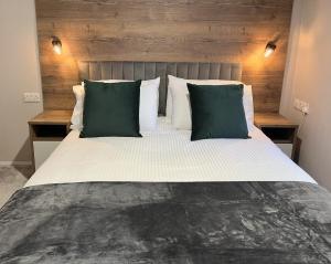 Silver Birch Lodge Aviemore في أفيمور: غرفة نوم بسرير كبير ومخدات خضراء وبيضاء