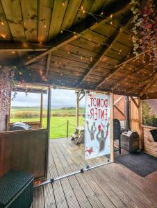 un porche de una casa con un cartel en FINN VILLAGE - Loch Lomond Sunset Glamping Pod - Private Ofuro HOT TUB, en Drymen