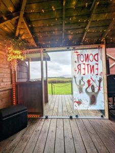 una puerta a un porche con vistas a un campo en FINN VILLAGE - Loch Lomond Sunset Glamping Pod - Private Ofuro HOT TUB en Drymen