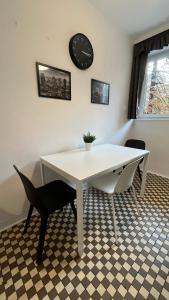 a white table with two chairs and a clock on the wall at Warszawa Krucza Pokoje in Warsaw