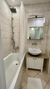 ein Badezimmer mit einer Badewanne, einem Waschbecken und einem Spiegel in der Unterkunft Warszawa Krucza Pokoje in Warschau
