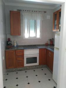 a kitchen with wooden cabinets and a white stove top oven at Casa en el centro del pueblo in Conil de la Frontera