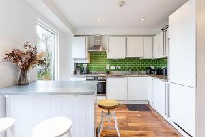 a kitchen with white cabinets and a wooden floor at 3 Bed Luxury Penthouse in Shoreditch in London
