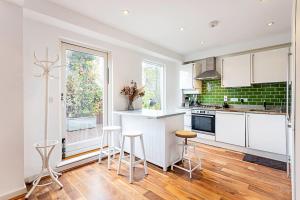 a kitchen with white cabinets and bar stools at 3 Bed Luxury Penthouse in Shoreditch in London