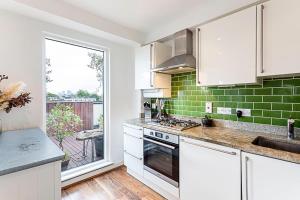 a kitchen with white cabinets and green tiles at 3 Bed Luxury Penthouse in Shoreditch in London