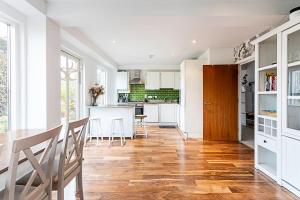 a kitchen and dining room with white cabinets and wood floors at 3 Bed Luxury Penthouse in Shoreditch in London