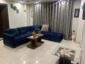 a living room with a blue couch and a table at Dha hotel apartments families only in Rawalpindi