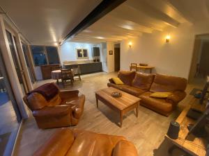 a living room with leather couches and a table at Apatam-Montigny, bord du Loing in Bourron-Marlotte