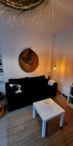 La Baule, Plein Centre/Terrasse في لا بول: غرفة معيشة مع أريكة سوداء وطاولة بيضاء