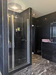 een badkamer met een douche met zwarte tegels bij FINN VILLAGE - Loch Lomond Villa B&B with a Hot Tub in Glasgow