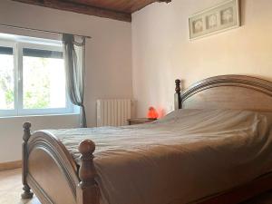 um quarto com uma cama de madeira e uma janela em Location gite entre Cahors et St Cirq Lapopie em Arcambal