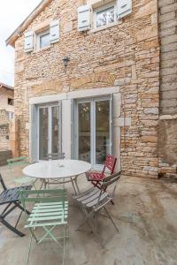 une table et quatre chaises devant un bâtiment en briques dans l'établissement Cabana & La Grange Maison Mâcon Nord, à Saint-Martin-Belle-Roche