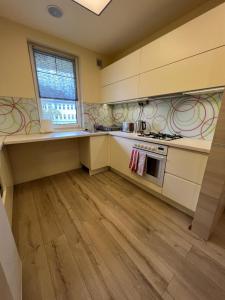 a kitchen with white cabinets and wooden floors and a window at City Lux Apartman in Nyíregyháza