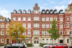 a large brick building with cars parked in front of it at EasyApartments stilvoll zentral Balkon Hauptbahnhof NETFLIX 130m2 in Hof