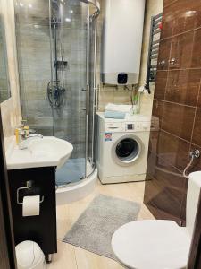 a bathroom with a shower and a sink and a washing machine at Apartament Sunny Home in Nowy Targ