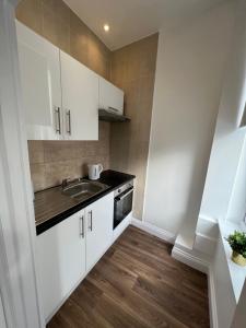 a kitchen with white cabinets and a sink at Excellent West Hampstead Studio in London