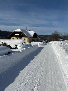 a snow covered road in front of a house at Apartmany215 in Strážné