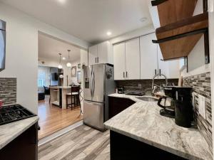 a kitchen with white cabinets and a stainless steel refrigerator at Perfect WFH Fishtown Townhouse with Private Patio in Philadelphia