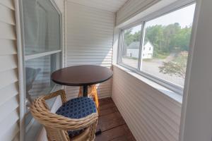 een veranda met een tafel, een stoel en een raam bij Inn by the River in The Forks