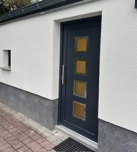 una puerta azul en el lateral de un edificio en ruhig wohnen im kleinen Bungalow im Süden von Berlin, en Teltow