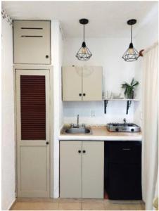uma cozinha com armários brancos e um lavatório em Anana Coliving em Playa del Carmen