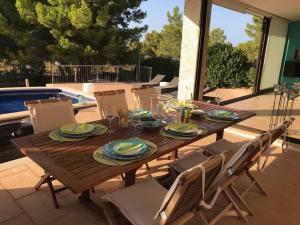 einen Holztisch und Stühle auf einer Terrasse in der Unterkunft Schöne meernahe Villa mit Pool+Grill, Nähe Artà in Colònia de Sant Pere