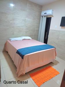 Bett in einem Zimmer mit orangefarbenem Teppich in der Unterkunft CASA DE TEMPORADA DE FÉRIAS in Santa Cruz Cabrália