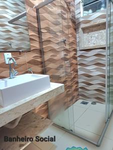 een badkamer met een wastafel en een glazen douche bij CASA DE TEMPORADA DE FÉRIAS in Santa Cruz Cabrália