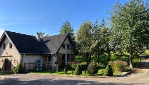 een wit huis met een zwart dak en bomen bij Dom Kopaczówka - sauna, home spa in Radków