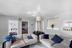 a living room with two white couches and blue pillows at Cozy 2 Bed Apartment Close to Excel, 02, & London City Airport! in London
