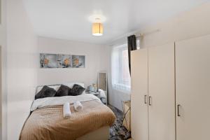 a bedroom with white walls and a bed with black pillows at Cozy 2 Bed Apartment Close to Excel, 02, & London City Airport! in London