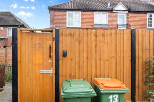 two trash cans in front of a wooden fence at Cozy 2 Bed Apartment Close to Excel, 02, & London City Airport! in London