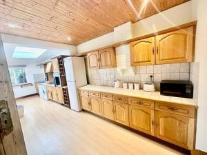 a kitchen with wooden cabinets and a white refrigerator at 4 Bed house in Daneby Road,SE6 in Catford