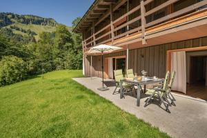 eine Terrasse mit einem Tisch, Stühlen und einem Sonnenschirm in der Unterkunft Waldgut in Oberstdorf