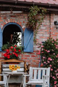 a table and two chairs in front of a building with flowers at Siedlisko Nad Miedwiem in Stargard