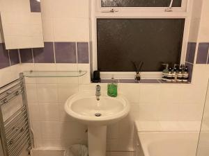 een witte badkamer met een wastafel en een raam bij Denis in Lincoln