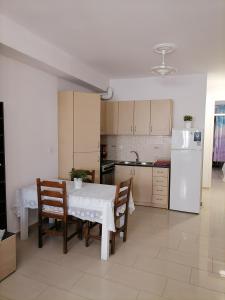 a kitchen with a table and chairs and a white refrigerator at PERGAMOS APARTMENTS in Mytilini