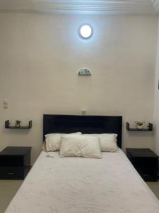 1 dormitorio con 1 cama blanca grande y 2 mesas en Chic-log, en Agbato