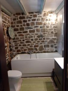 a bathroom with a white tub and a stone wall at Fairytale Stone House in Karpenision