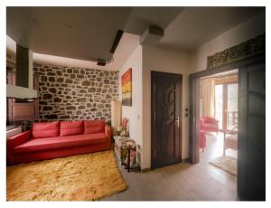 a living room with a red couch and a brick wall at Fairytale Stone House in Karpenisi